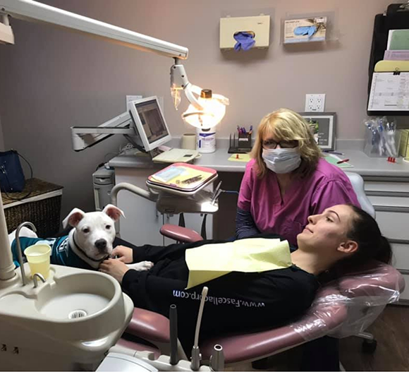 Woman in the dental chair petting a service dog