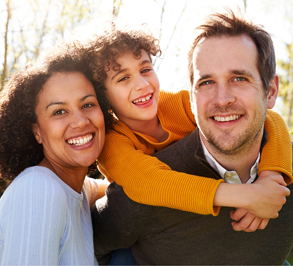 Family of three smiling outdoors after seeing a children's dentist in Doylestown