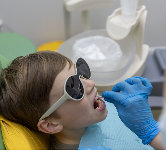 Child in the dental chair having fluoride applied to their teeth
