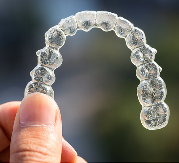 Hand holding a clear aligner