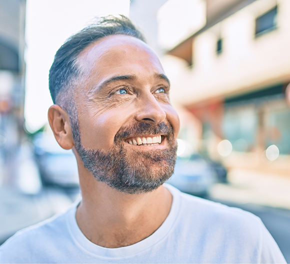 Bearded man smiling on a city sidewalk