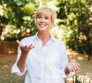 Older woman tossing an apple outdoors