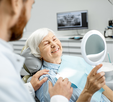Senior dental patient admiring her smile in a mirror