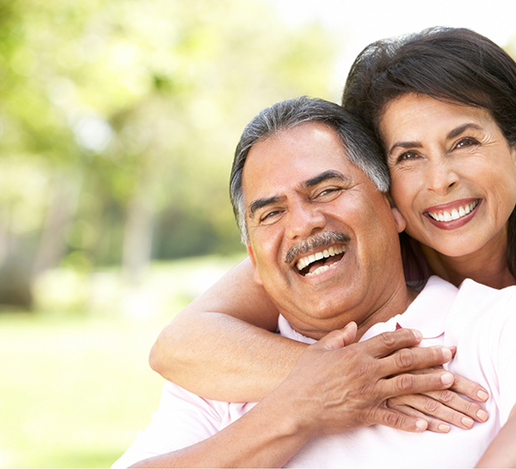 Older couple smiling outdoors with dentures in Doylestown