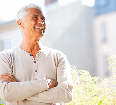 Senior man smiling in the sunlight with his arms crossed