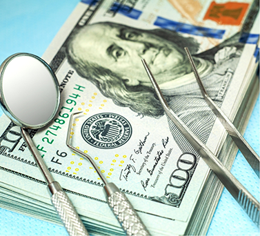 Dental instruments on top of a stack of hundred-dollar bills