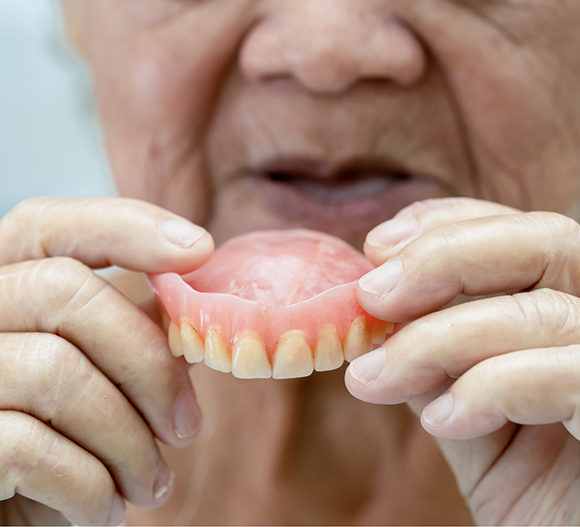 Senior woman holding her denture