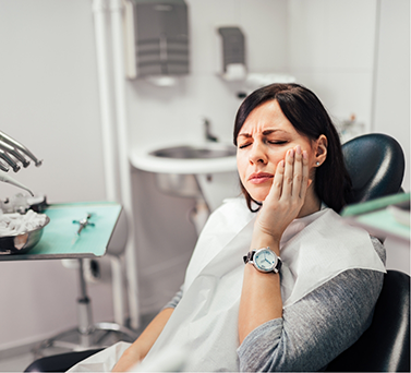 Dental patient holding her cheek in pain