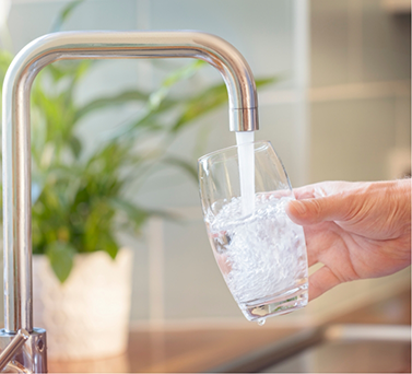 Person filling a glass of water in the sink