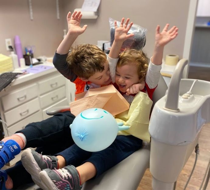 Two young kids cheering in the dental chair at a dental office in Doylestown