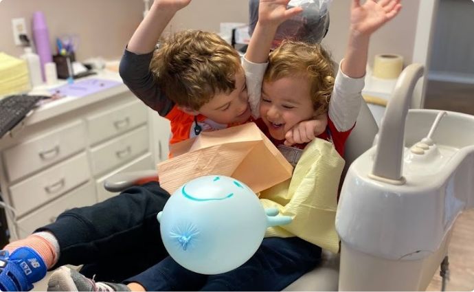 Two young children cheering in the dental chair
