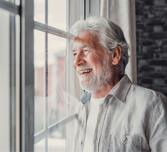 Smiling senior man looking out of a window