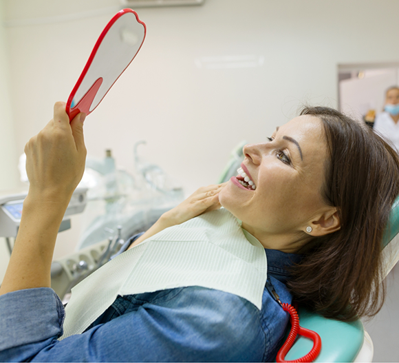 Dental patient admiring her smile in a mirror