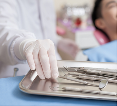 Dentist selecting an instrument while treating a patient