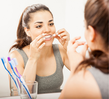 Woman placing a whitening tray over her teeth