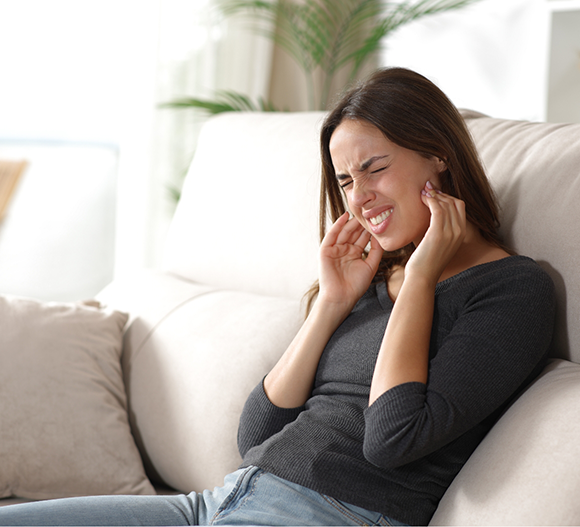 Woman holding both sides of her jaws in pain