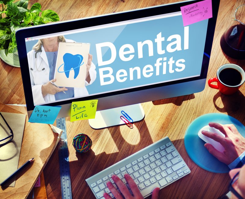 A desk with a computer screen displaying the text Dental Benefits alongside a tooth graphic.