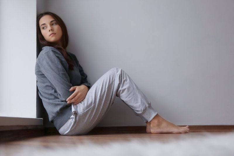 Depressed young woman sitting on floor.