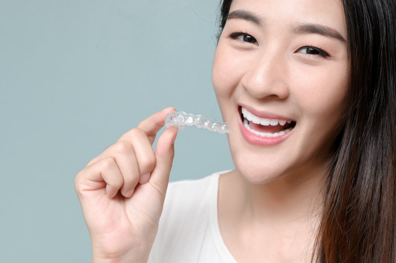 Person holding Invisalign and smiling.