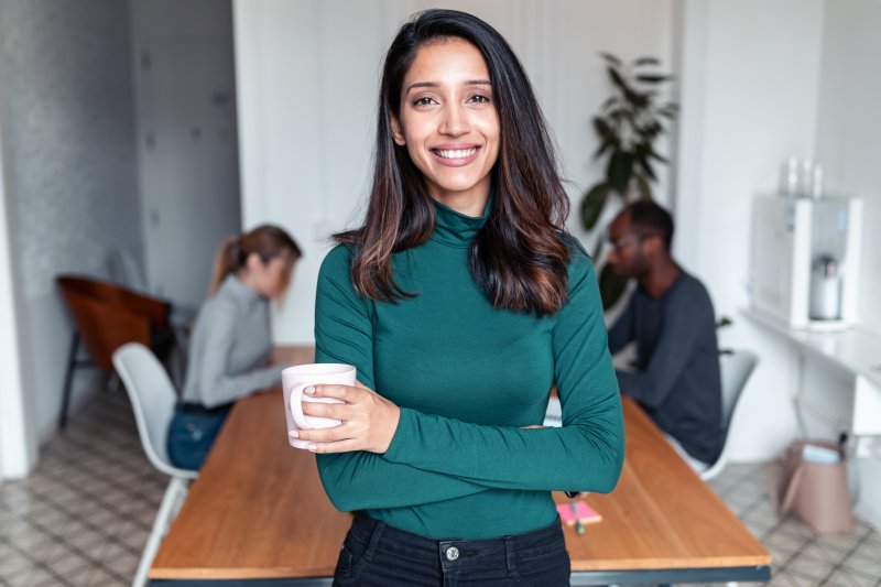 Woman smiling with Invisalign aligners in front of a business table.