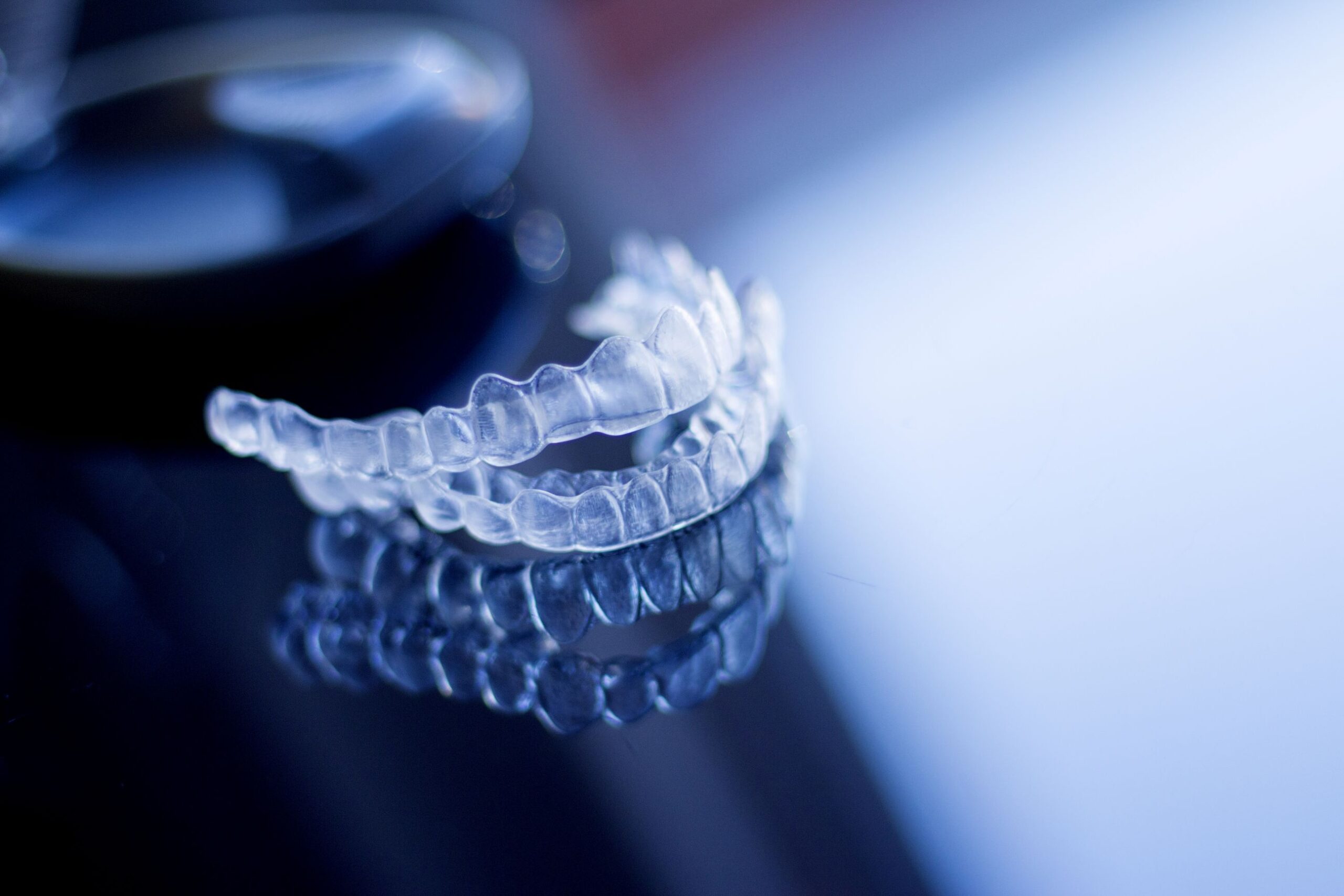 Clear aligners on a reflective dark surface.