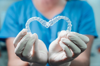 Dentist holding Invisalign aligners in the shape of a heart.