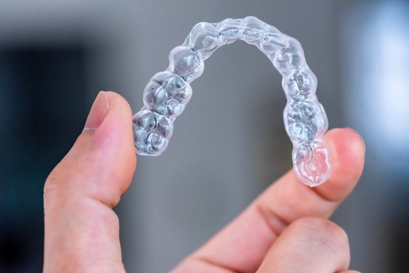 A person holding an Invisalign aligner.